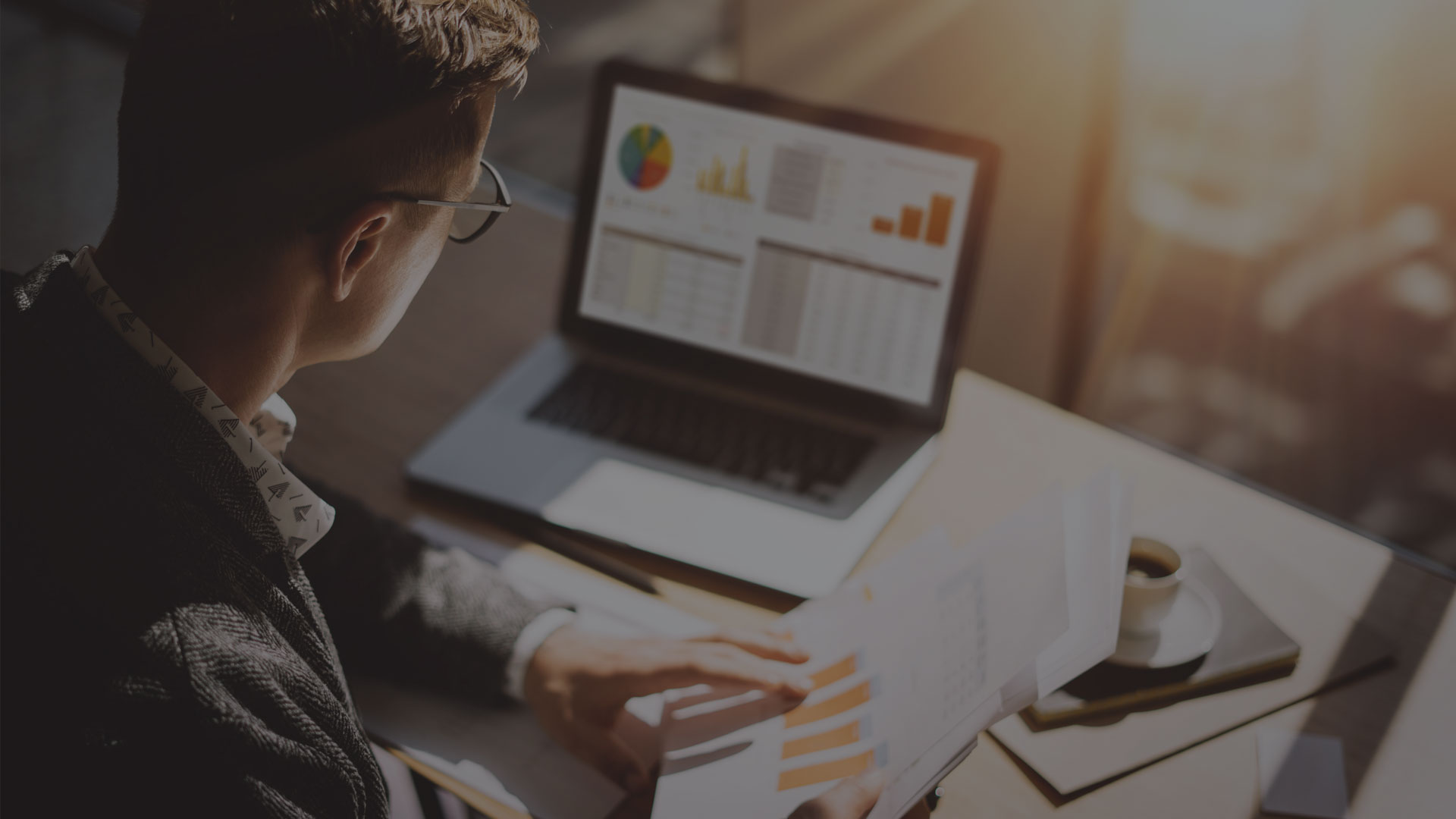 Transaction Management | Image of person working on laptop and comparing numbers on a paper to numbers on screen