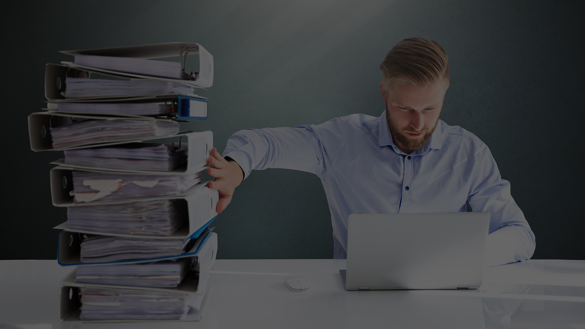 Paper Digitization: Why We’re Not Letting Go of Paper Man looks at computer while pushing a large stack of binders away