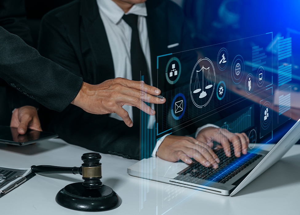 Person typing on laptop with another person reaching over their shoulder to touch a holographic icon 