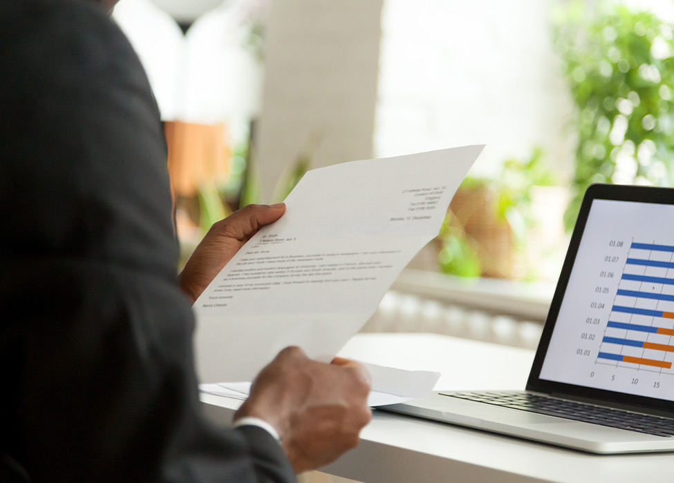 Outsourcing Mail | Person looking at a piece of paper and their laptop screen